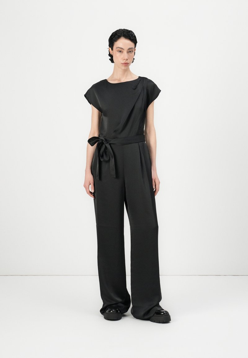 Jardín negro con mangas cortas, escote redondo, cinta en la cintura y pantalones de pierna ancha, hechos de una tela suave y ligera.