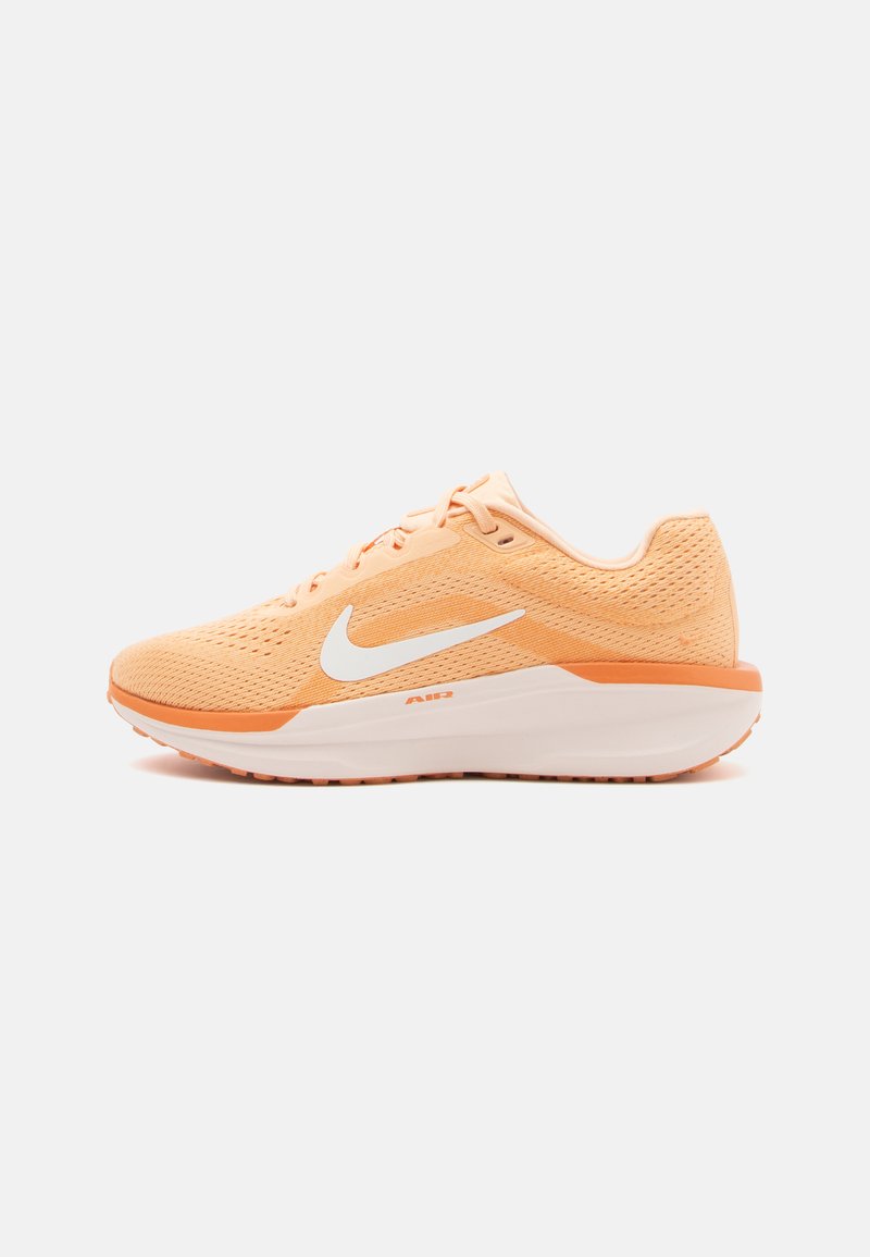 Shoe desportivo laranja claro com parte superior em malha, swoosh branco da Nike, entressola branca acolchoada e sola exterior de borracha texturizada.