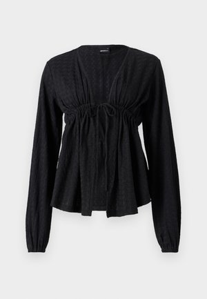 Czarna, długosleeve, teksturowana bluzka z dekoltem w serek, zgromadzoną talią, detalem w postaci wiązania i rozkloszowanym dołem. Miękka tkanina z subtelnym wzorem.