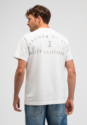 T-shirt en coton blanc pour homme avec le texte « Butcher of Blue » en lettres délavées au dos. Manches courtes et coupe décontractée. Design casual.