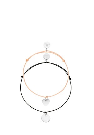 Zwei verstellbare Kordelarmbänder, eines pfirsichfarben mit einem silbernen Herzanhänger, eines schwarz mit einem silbernen runden Anhänger, beide mit gebrandeten runden Anhängern.