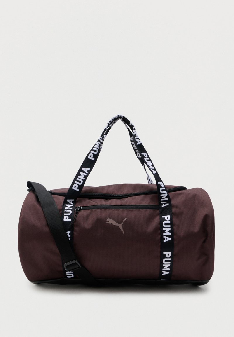 Καφέ τσάντα duffel Puma με λουράκια Puma σε μαύρο και λευκό, μπροστινή τσέπη με φερμουάρ και ρυθμιζόμενο μαύρο λουρί ώμου.