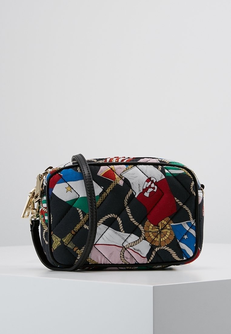 Petit sac bandoulière matelassé avec motif drapeau nautique et corde, bordure noire et détail de fermeture éclair dorée, reposant sur une surface blanche.