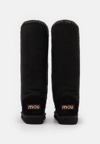 Botines negros de tobillo con un exterior de ante suave, parte superior redondeada y costuras en contraste. Presenta una pequeña etiqueta de marca en el talón.