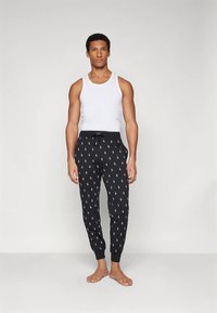 Μαύρο παντελόνι jogging με λευκά λογότυπα Polo, στενά μπατζάκια και ελαστική μέση με κορδόνι, σε συνδυασμό με λευκή αμάνικη μπλούζα.