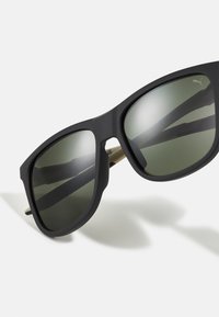 Fekete keretes napszemüveg matt felülettel, zöld lencsékkel, szögletes formával és diszkrét arany díszítéssel a szárakon.