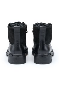Sorte ankelstøvler lavet af læder og ruskind, med flad sål, bageste trækflap og dobbelte sidezipper til nem påtagning.