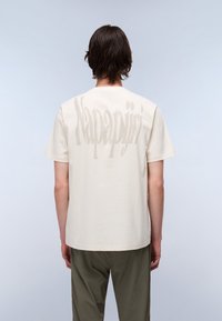 Beige cotton t-shirt featuring large tonal "Napapijri" text on the back. Crew neck, short sleeves, relaxed fit.