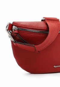 Borsa rossa in pelle con forma arrotondata, dotata di una zip argentata e di una tracolla in tessuto. Superficie texturizzata con una leggera lucentezza; design compatto.