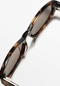 Želvovinové sluneční brýle s tmavými skly, širokými rámy, hladkým povrchem a jemným leskem. Kovové doplňky u pantu.