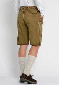 Suedeshorts i olivgrönt med en avslappnad passform, med en sidoficka, dekorsömmar och bruna detaljer. Kombineras med krämfärgade strumpor.