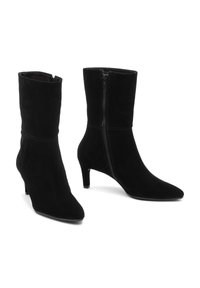 Botas de tacón negro de ante, con punta afilada y un tacón delgado, que cuentan con una cremallera lateral y detalles de costura sutiles.
