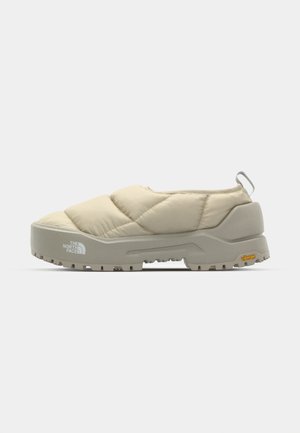 Quilted beige slip-on sko med grå Vibram sål, rund form og bageste løkke. Har logo på siden og struktureret overflade.
