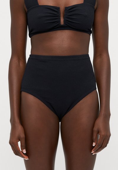 Sort bikini-top med samlet front og brede stropper, parret med højtaljede sorte bunde. Tekstureret stof, sømløs design.