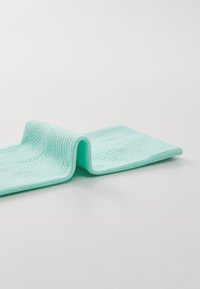 Tejido de punto verde menta, texturizado con estrías, doblado, mostrando un material suave y transpirable.