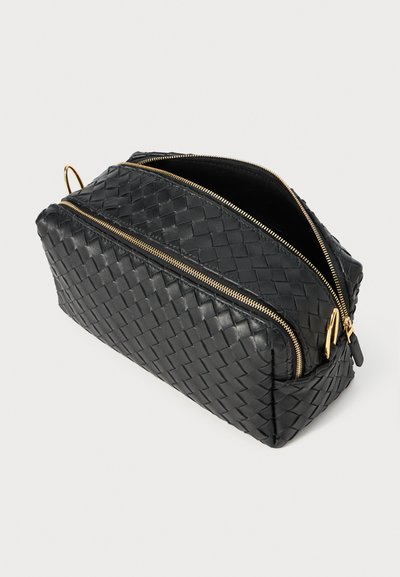 Borsa nera in pelle intrecciata con forma rettangolare, doppie chiusure con zip dorate e apertura superiore. Presenta una superficie texturizzata e un interno liscio.
