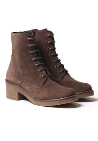 Bottines en suède marron avec un lacet à l'avant, un talon robuste et un bout arrondi. Comprend des œillets en métal et un détail de couture contrastant.