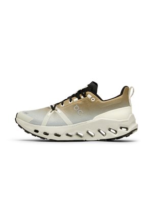 Chaussure de course légère beige et blanche avec des lacets noirs, semelle ventilée et languette de traction au talon, vue de profil latéral.