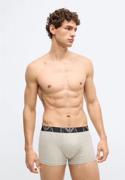 Szare bawełniane bokserki z czarnym paskiem w logo, o dopasowanym kroju i gładkiej fakturze, prezentowane na modelu męskim.