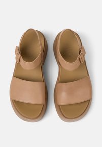 Bruna lädersandaler med breda remmar, justerbart spänne, rund tå och platt gummisula, med en slät yta och minimalistisk design.
