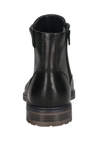 Bottine en cuir noir avec zip sur le côté, couture visible et semelle superposée marron et noire, vue de l'arrière.