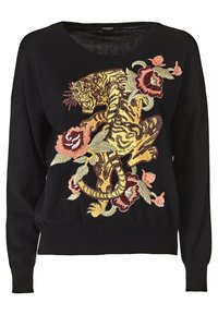 Pull en maille noir avec une broderie de tigre vibrante entourée de motifs floraux dans des couleurs comme l'or, le rouge et le vert. Coupe décontractée, décolleté en V.
