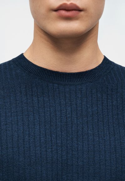Pull bleu marine côtelé avec un col rond, en tissu texturé, présentant de larges côtes et un tricot doux et uniforme.