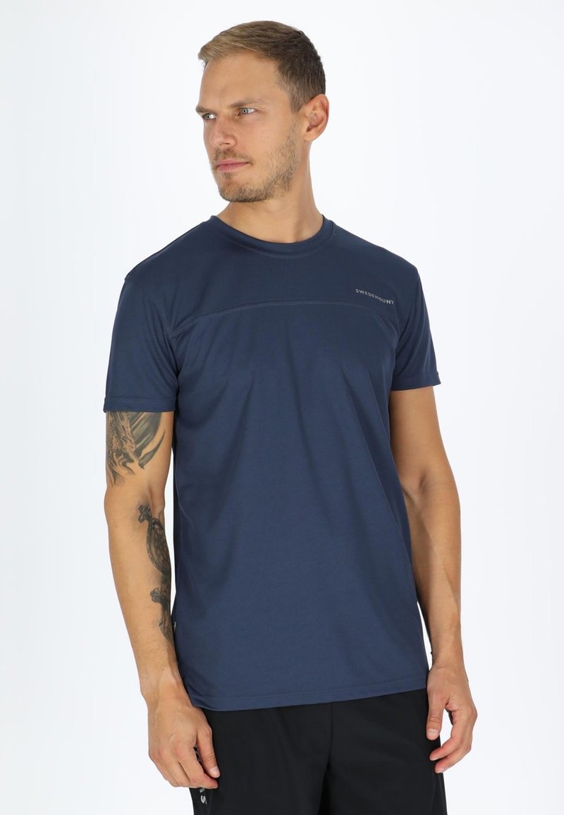 Mørkeblå atletisk t-shirt lavet af letvægtigt stof, med korte ærmer, rund halsudskæring og et diskret logo på brystet.