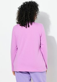 Maglietta a maniche lunghe in tessuto viola chiaro, caratterizzata da un taglio dritto e dettagli minimi, abbinata a pantaloni viola coordinati.