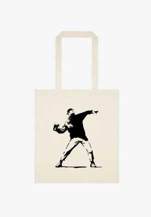 Beige bomulds tote bag med en sort silhuet af en figur, der kaster maling, iført kasket og med tekstur i tøjdetaljerne.