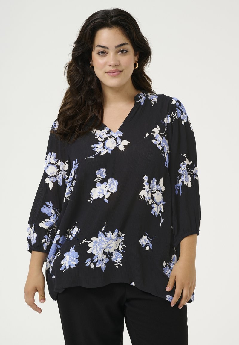 Zwarte bloes met bloemmotieven in blauw en wit, zachte stof, 3/4 mouwen en een V-hals ontwerp. Loose fit met een gebogen zoom.