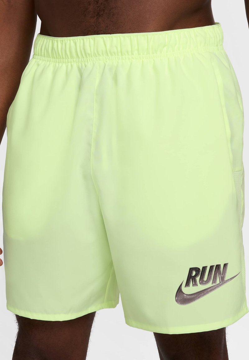 Shorts amarillos neón con cinturilla elástica, con un gráfico plateado que dice "RUN" y el logo de Nike. Tela suave y ligera.