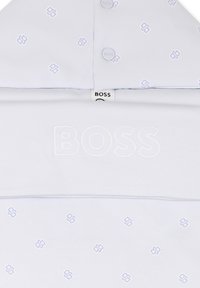 Polo shirt gris clair avec logo brodé et petits accents à motifs en bleu et blanc. Caractéristiques d'un col classique et d'une fermeture à boutons.