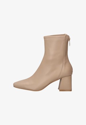 Bota de tobillo de imitación de piel beige con punta afilada, tacón cuadrado y detalle de cremallera lateral para facilitar su uso. Textura suave y diseño minimalista.