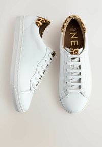 Baskets en cuir blanc avec des lacets blancs et des détails imprimés léopard sur le talon et la languette, vues de dessus et de côté.