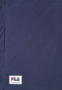 Námořnická modrá, odolná látka; obsahuje vyšívanou logovou nášivku s červenými a bílými akcenty; hladká textura, jednoduchý design, bez viditelných vzorů.