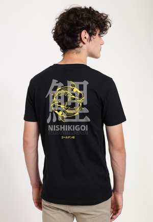 Hombre de espaldas lleva una camiseta negra con un pez koi amarillo, kanji japonés y la palabra "Nishikigoi" impresos en la parte trasera.