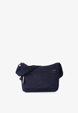 Marineblå crossbody taske med justerbar rem, front lynlåslomme og diskret brandlogo på en ensfarvet hvid baggrund.