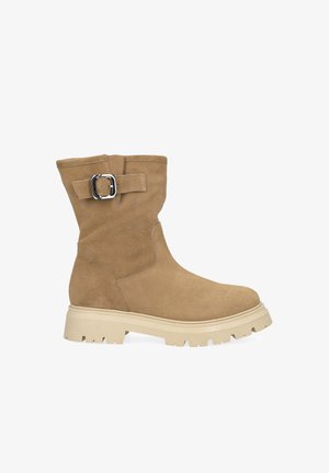 Botte mi-mollet en daim beige avec semelle épaisse beige et bride à boucle argentée sur le côté, vue du côté extérieur.