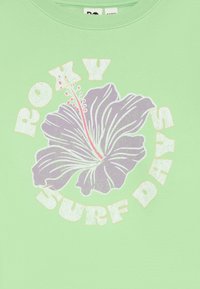 Žalias džemperis su purpuru hibisko grafika ir rožiniais akcentais, o tekstas "ROXY SURF DAYS" parašytas ryškiomis baltomis raidėmis.