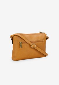 Bolso cruzado de cuero marrón claro con una textura suave, que cuenta con un compartimento principal con cremallera y un bolsillo frontal, correa ajustable y adornos dorados.
