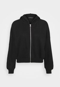 Felpa nera con zip realizzata in un morbido tessuto, con orlo aderente, maniche oversize e cappuccio con cordino. Presenta una zip liscia di colore argento.