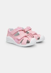 Roosa sandaalid kahe reguleeritava Velcro rihmaga ees, valge kummitald ja hingav võrgudetail külgedel.
