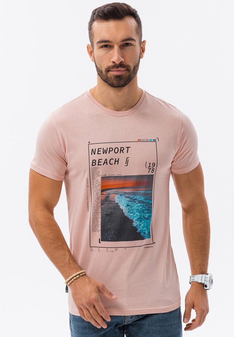 Vaaleanpunainen t-paita, jossa on Newport Beach -graafinen kuva auringonlaskusta meren aaltojen yli. Lyhyet hihat, pyöreä kaula-aukko ja pehmeä rakenne.