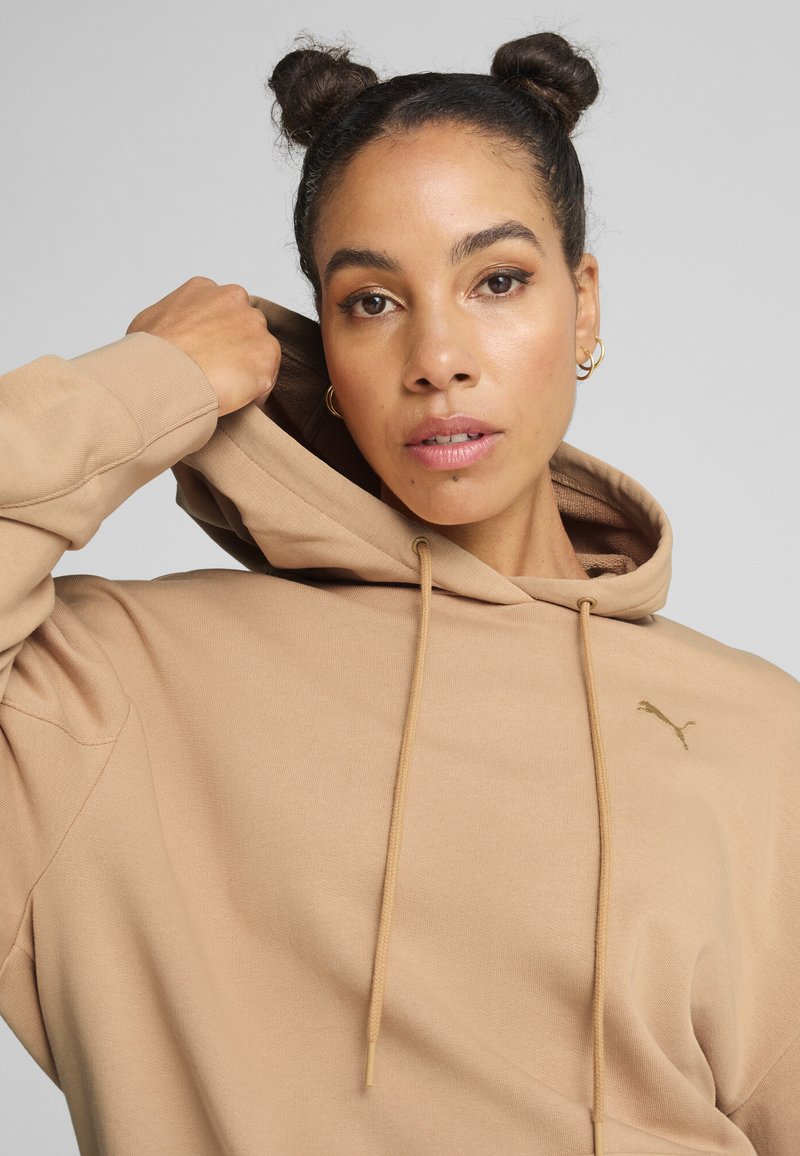 Felpa beige con tasca a marsupio, cappuccio con lacci e logo dorato sul petto. Tessuto morbido con una finitura liscia e vestibilità comoda.