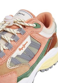 Baskets avec un mélange de daim rose, de maille grise et d'accents verts. Lacets ronds et logo bien visible sur une languette blanche. Semelle épaisse blanche.