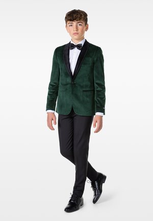 Grüner Samtblazer mit schwarzen Satin-Revers, weißem Hemd, schwarzer Fliege, schwarzen Hosen und polierten schwarzen Schuhen.