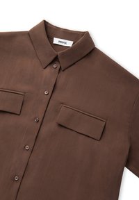 Brązowa bluzka krótki rękaw z kołnierzykiem, z dwoma kieszeniami na piersi, z zapięciem na guziki oraz gładką, lekką fakturą.