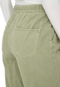 Pantaloni in misto cotone verde chiaro con vita elasticizzata. Presentano due tasche posteriori con flap rettangolari e una texture liscia.