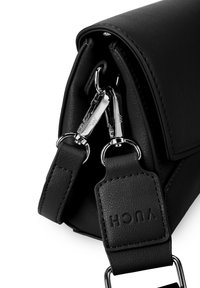 Černá kabelka z umělé kůže s texturovaným povrchem, stříbrnými kovovými prvky, nastavitelným popruhem a výrazným logem značky vyraženým na popruhu.